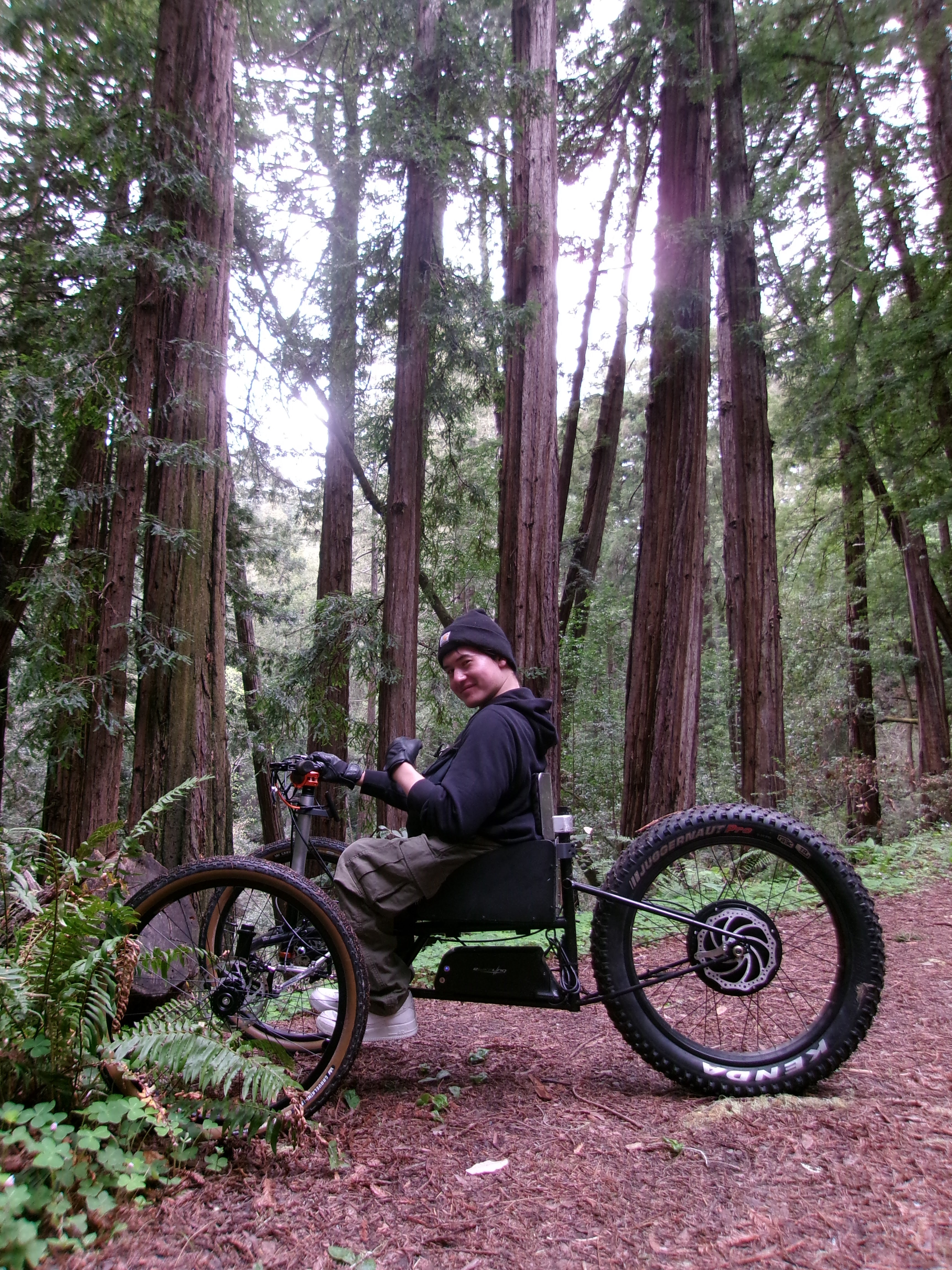 Side profile rider photo of the physical KOINE prototype in a forest setting